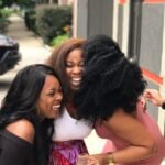 Group of young women laughing together while looking at a phone