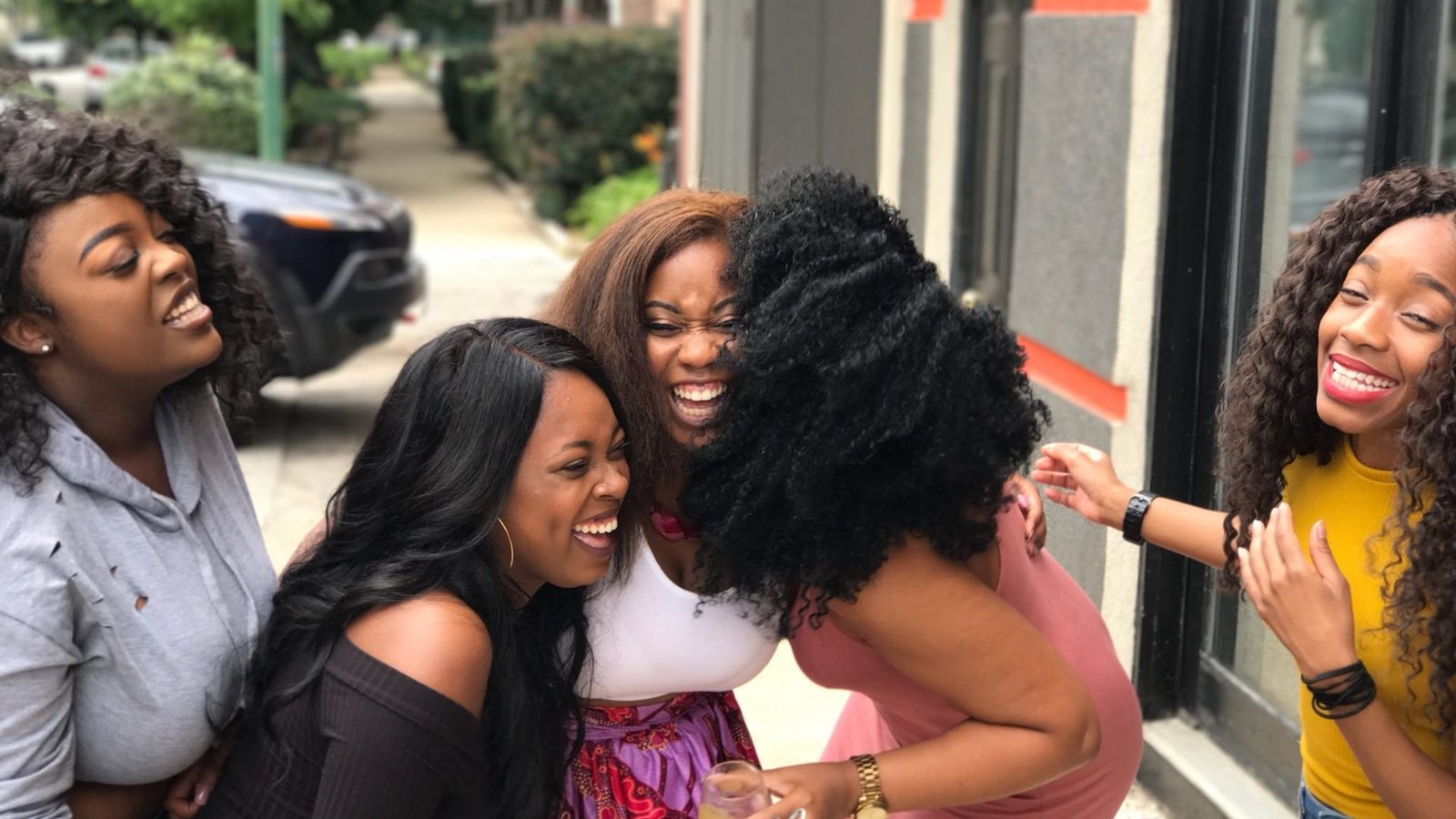 Group of young women laughing together while looking at a phone