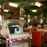 Retro 1950s diner interior with a jukebox, red booths, and chrome details