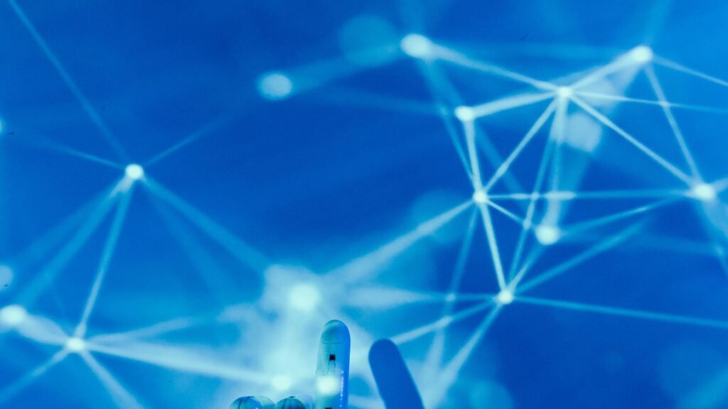 Robotic hand touching a glowing digital network on a blue background, a visual metaphor for artificial intelligence