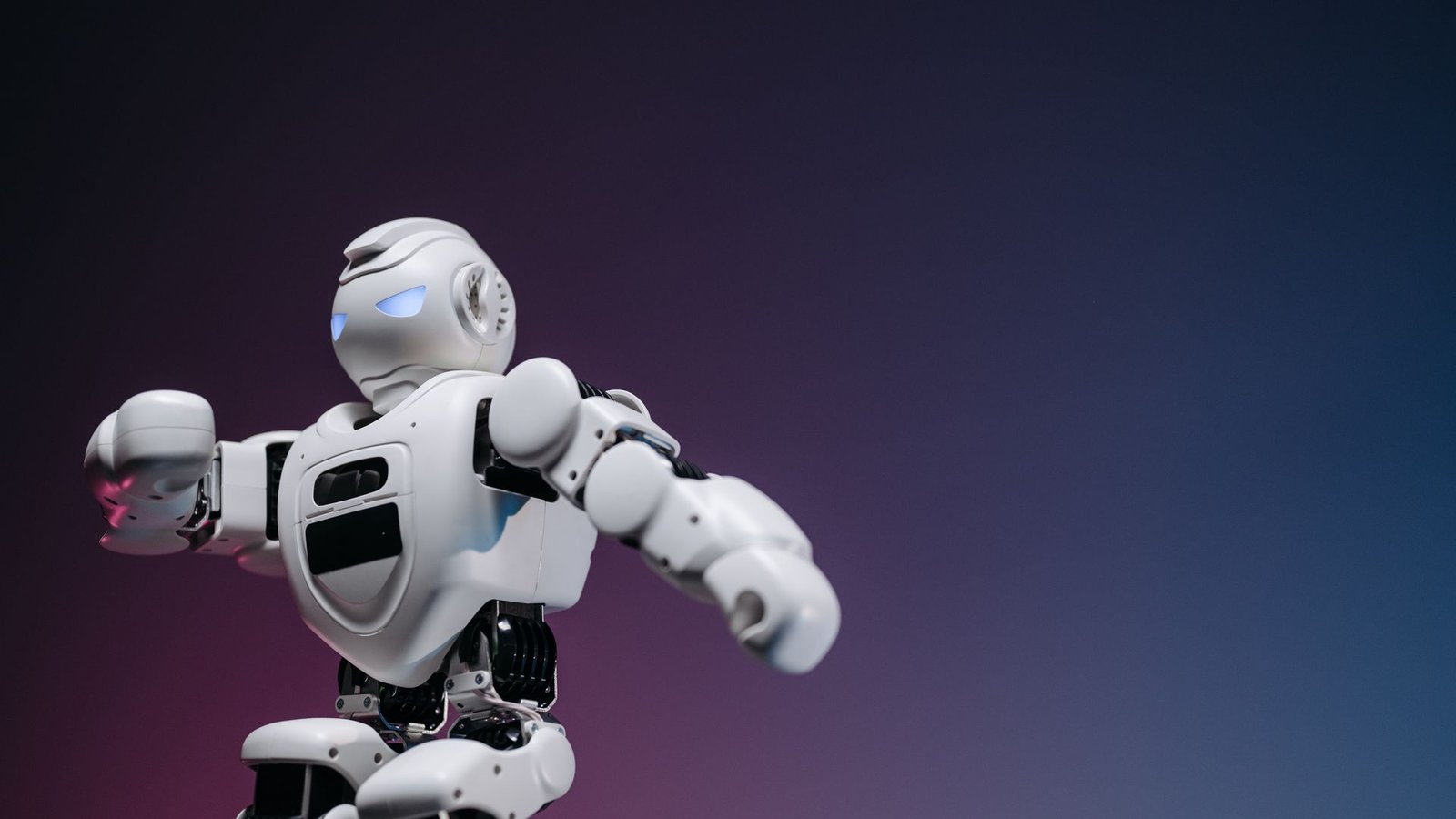 Small white toy robot photographed against a blue and pink gradient background