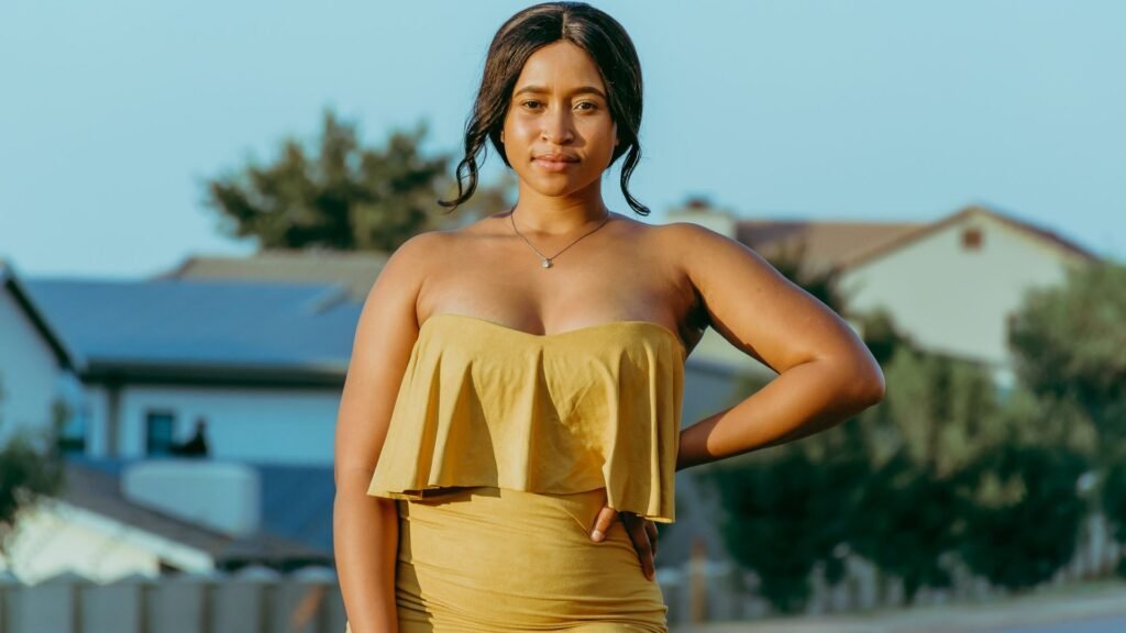 Confident plus-size woman in a yellow dress posing outdoors