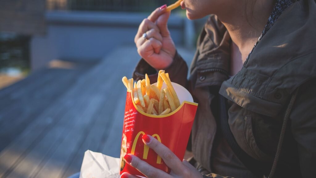 Woman eating French fries outdoors on a sunny day