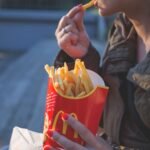 Woman eating French fries outdoors on a sunny day