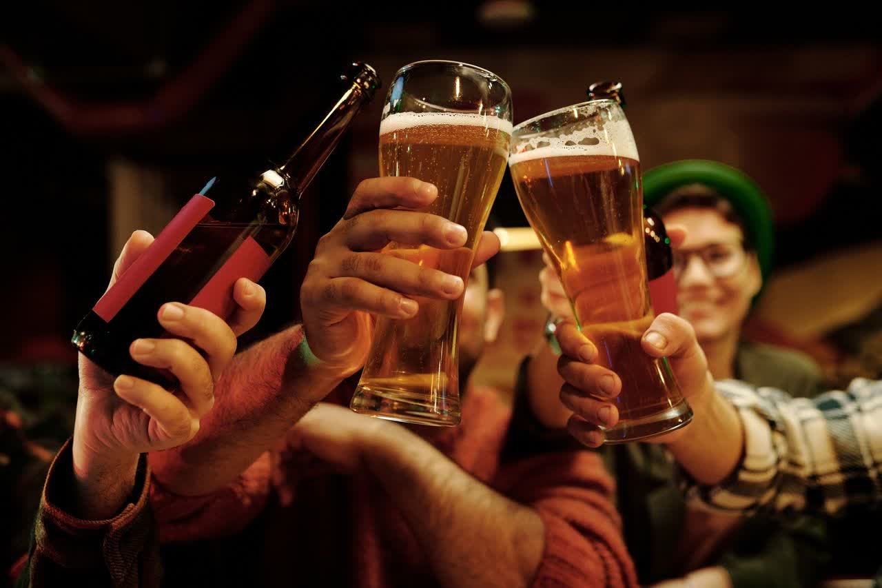 Group of friends toasting with beer glasses in a pub, the classic setting for British banter and playful insults